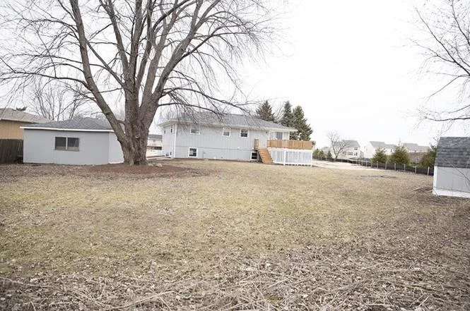 Two-story white house with newly installed roof and large bare tree in yard