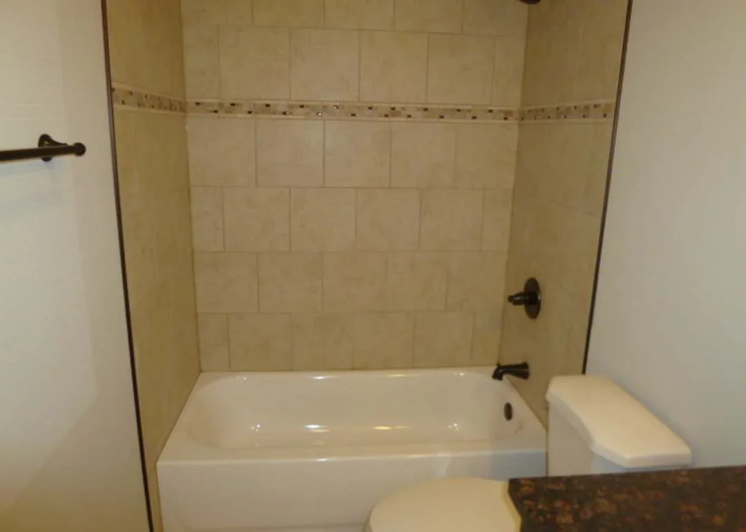 Restored bathroom with new ceramic tile shower surround and white fixtures