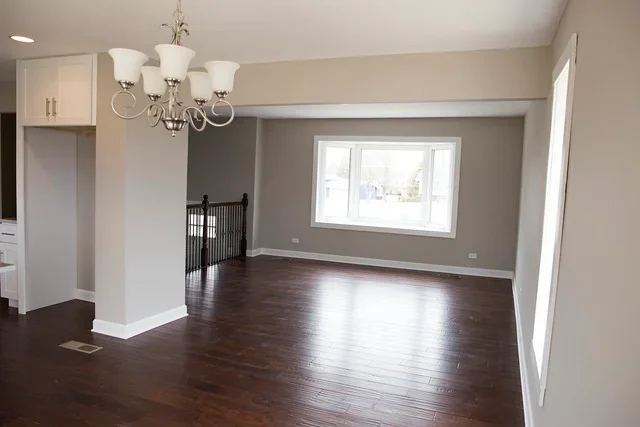 Bright open living room with dark hardwood floors, neutral walls, and modern chandelier