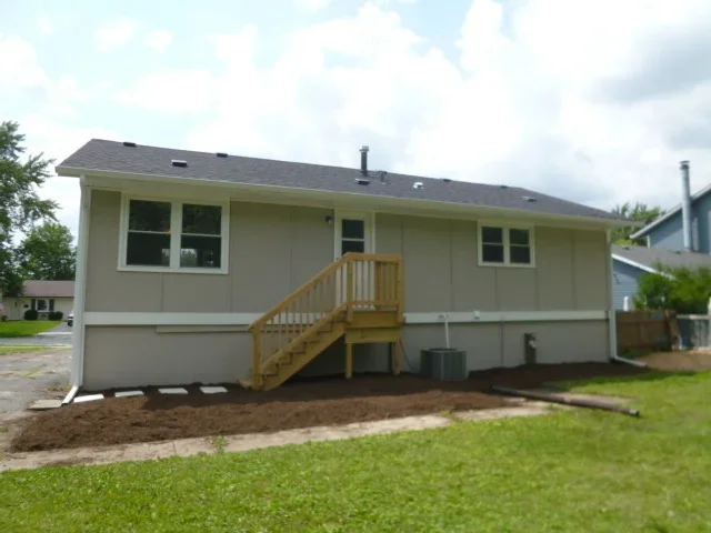Elevated home with new asphalt roof, painted siding, and wooden deck stairs