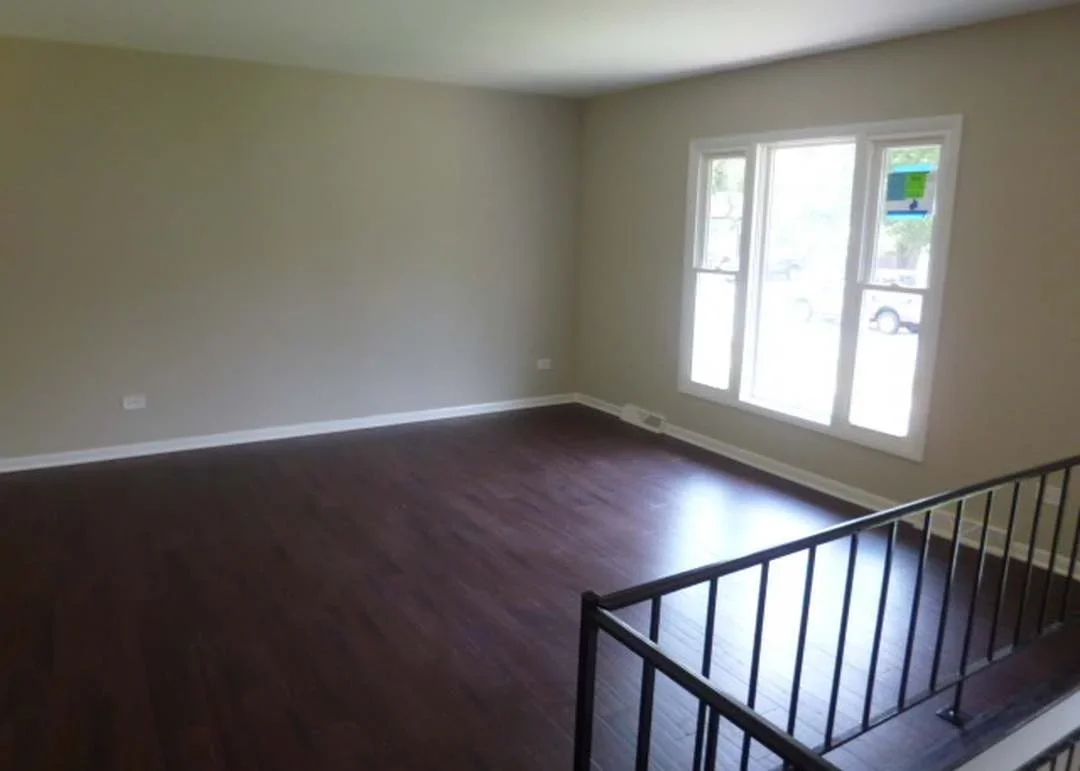 Restored interior room with dark hardwood floors, neutral walls, and triple-pane glass doors