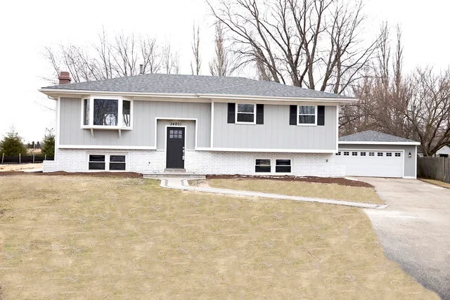 White split-level home with newly installed gray asphalt shingle roof and attached garage