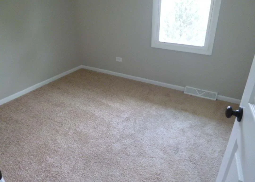 Newly installed beige carpet in bedroom with white trim and baseboard molding
