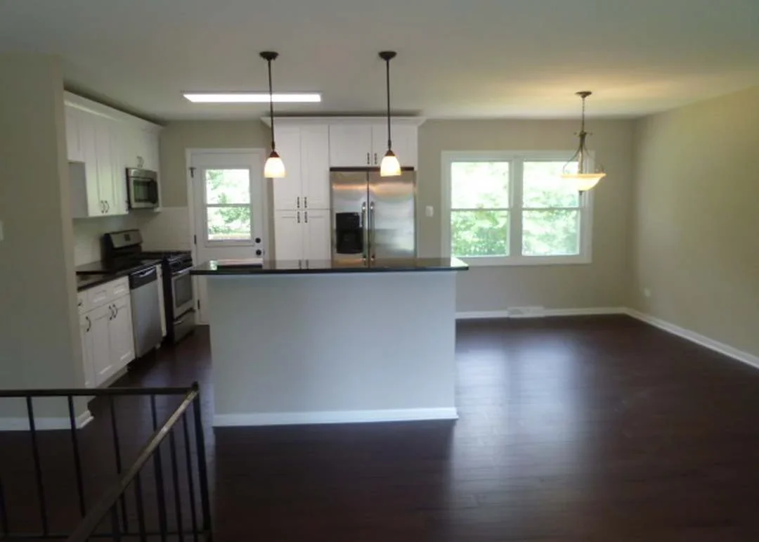 Modern kitchen with white cabinets, stainless steel appliances, and pendant lights over island