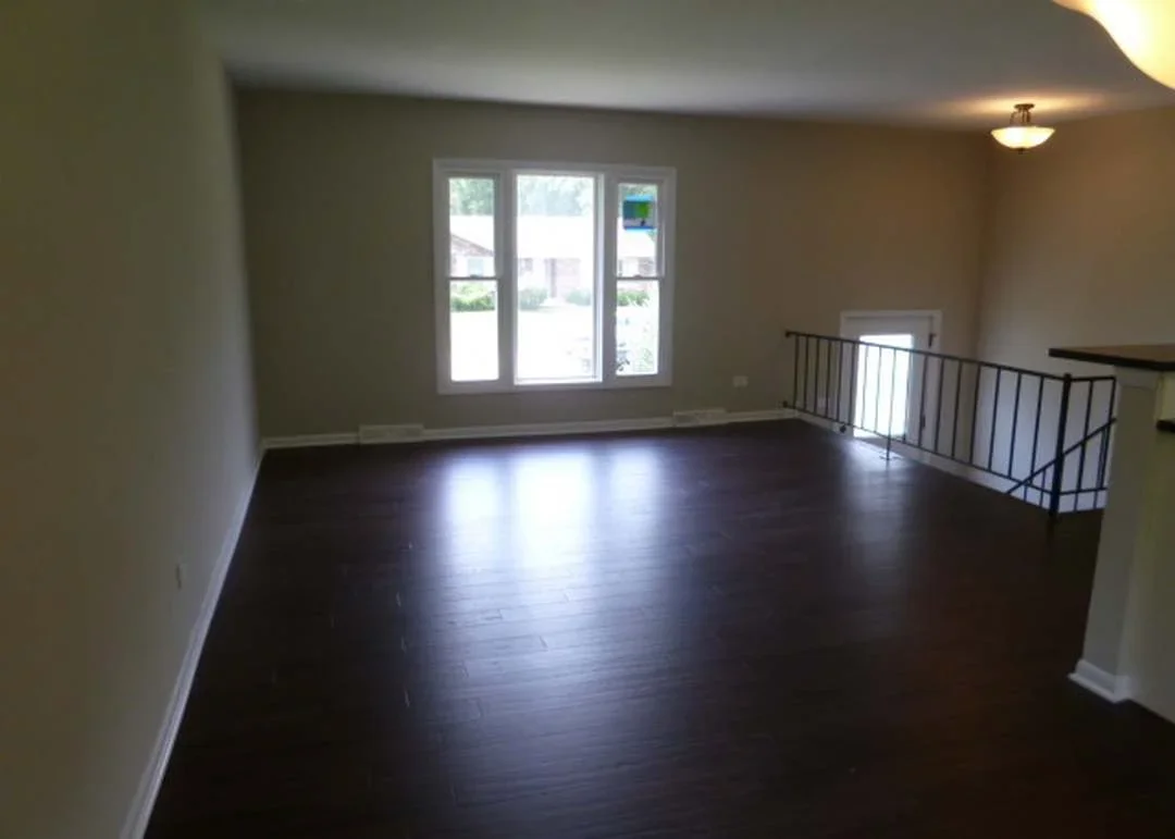Restored loft interior with dark hardwood floors, neutral walls, and metal railing