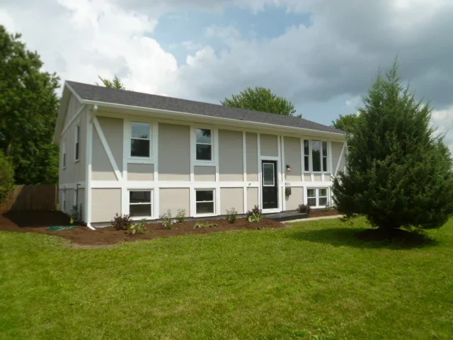 Two-story home with new roof, cream siding, white trim, and manicured lawn