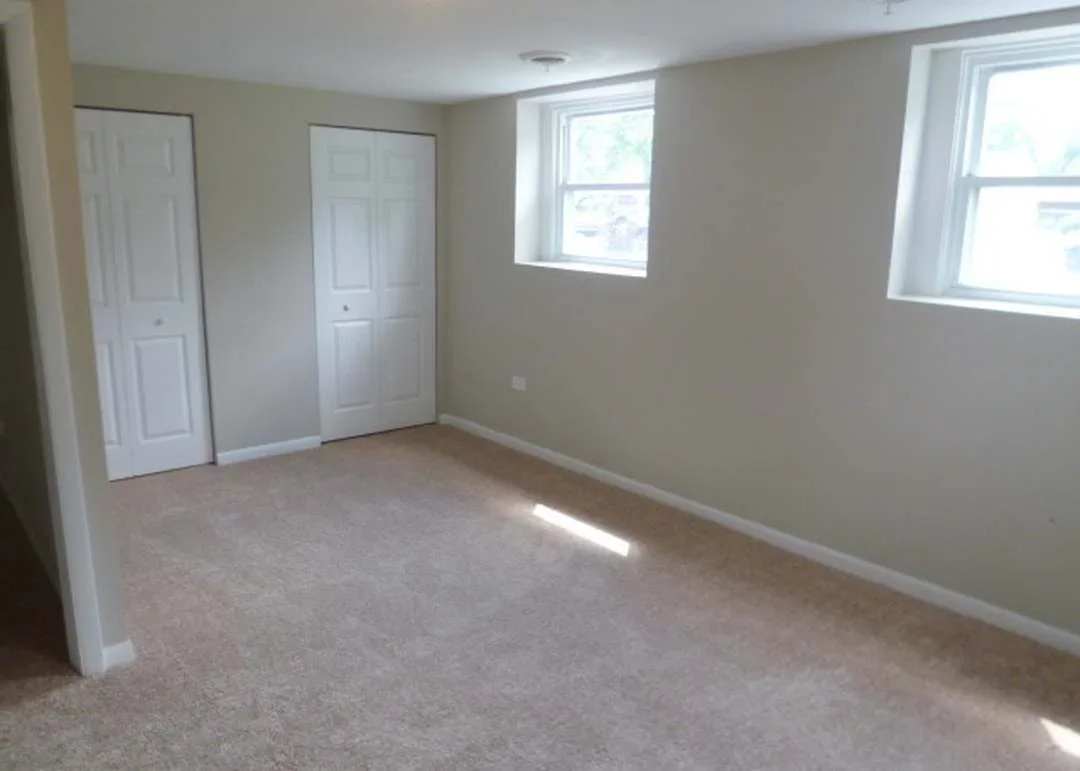 Restored interior room with beige walls, carpet flooring, white doors, and windows