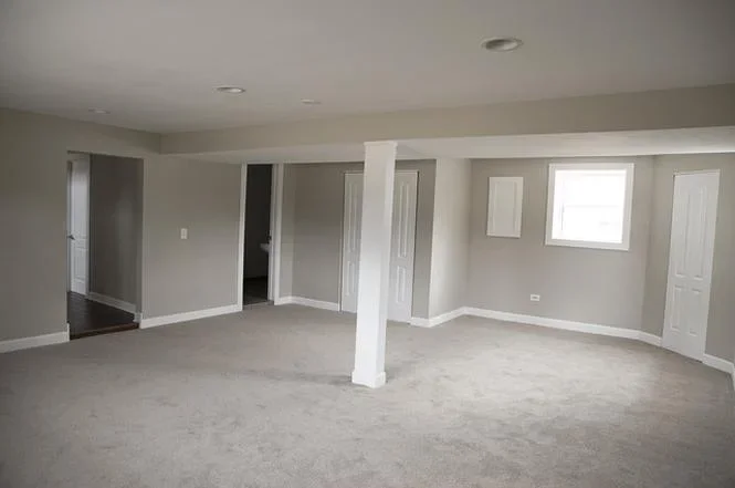 Finished basement interior with drywall, recessed lights, white trim doors, and concrete floor