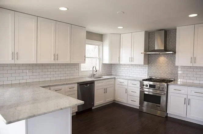 White kitchen with quartz counters, subway tile backsplash, and stainless steel appliances